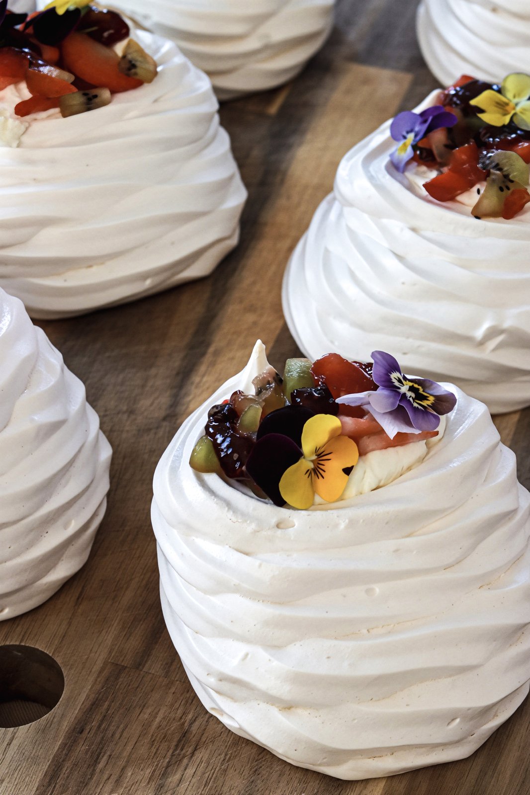 Mini pavlovas topped with fruit and edible flowers