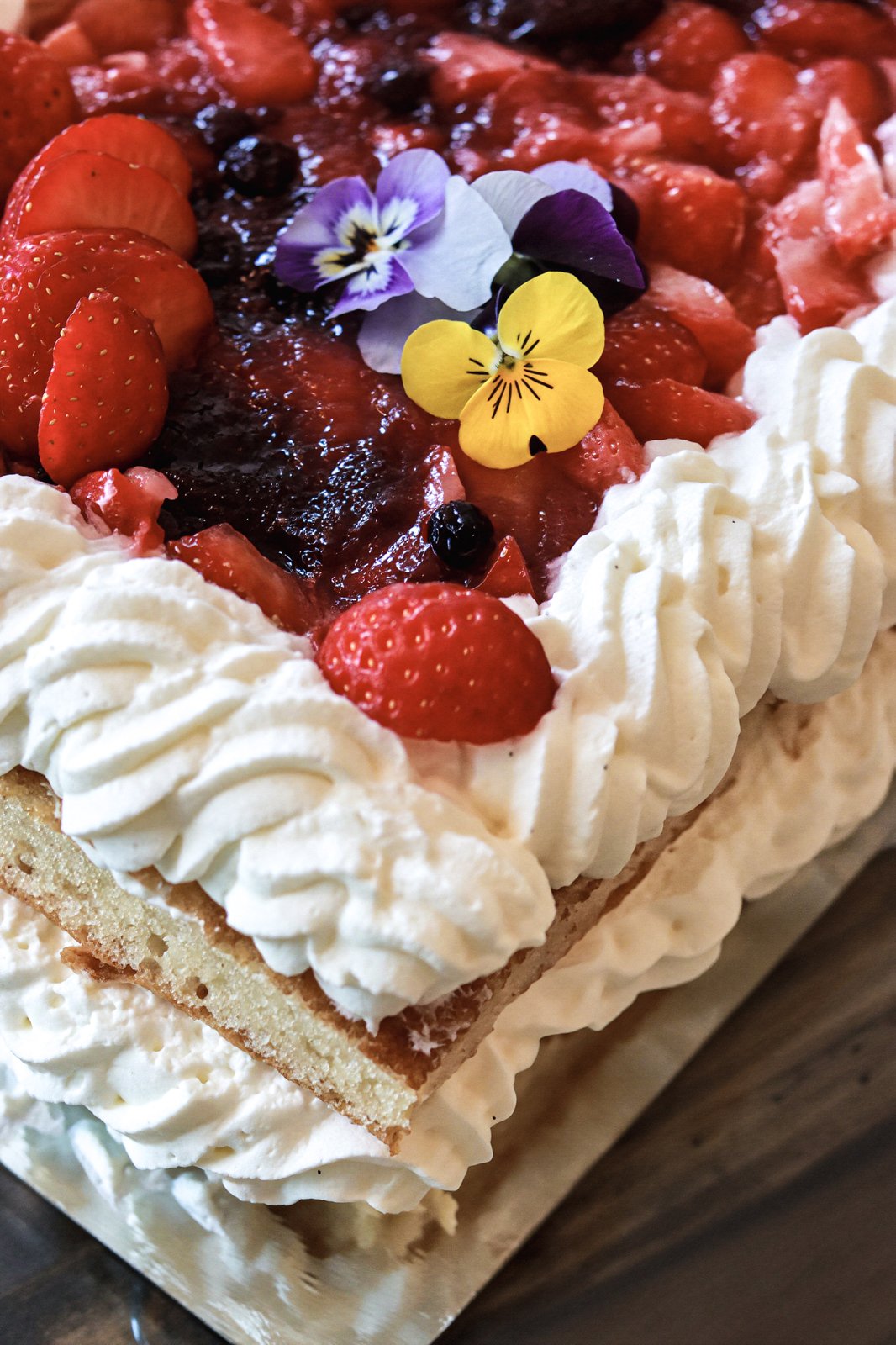 Strawberry and berry layer cake with cream and edible flowers